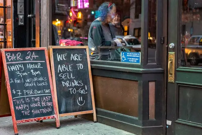 A sign advertising to-go drinks outside a bar